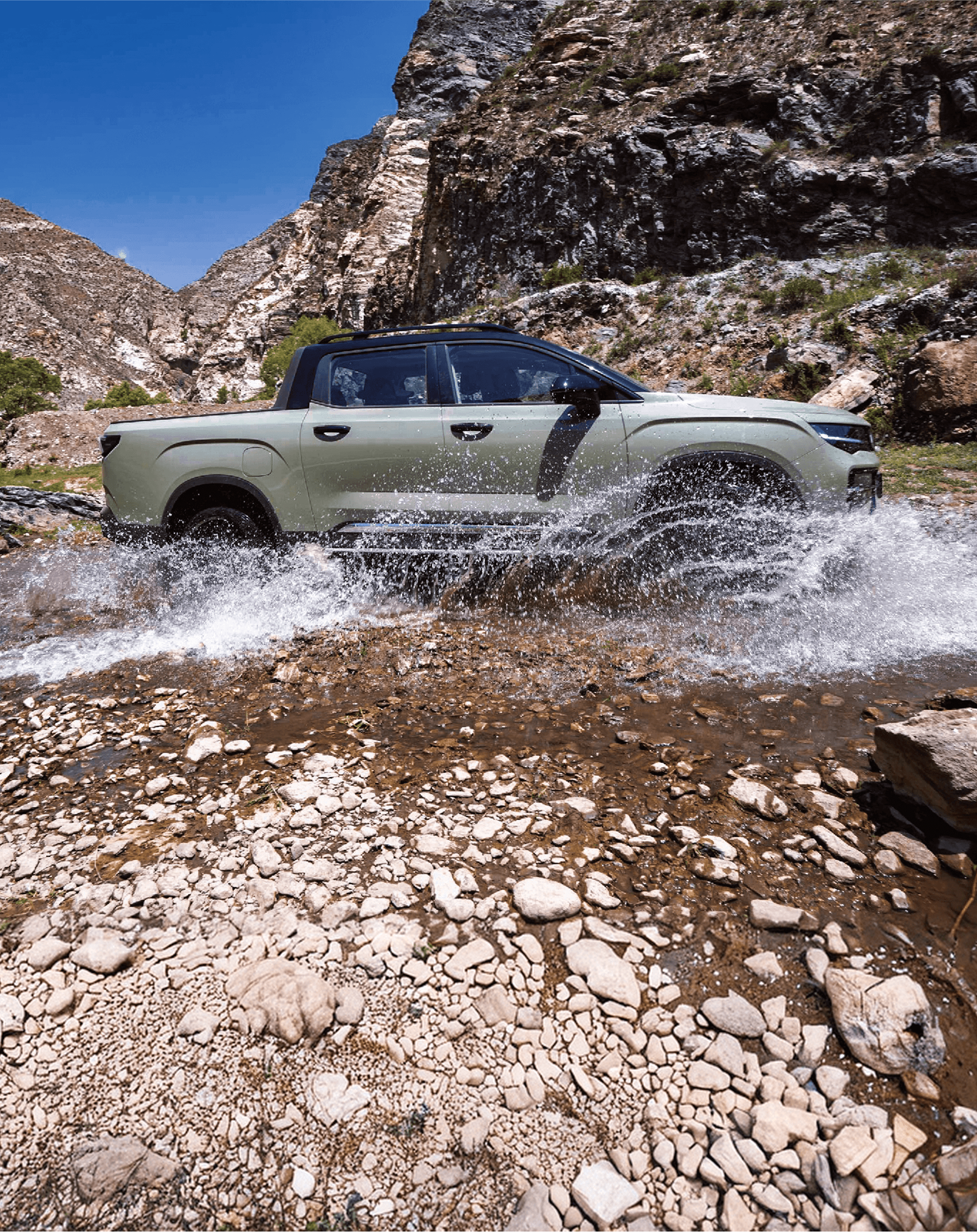 Geely Riddara driving through a rocky stream in mountain terrain