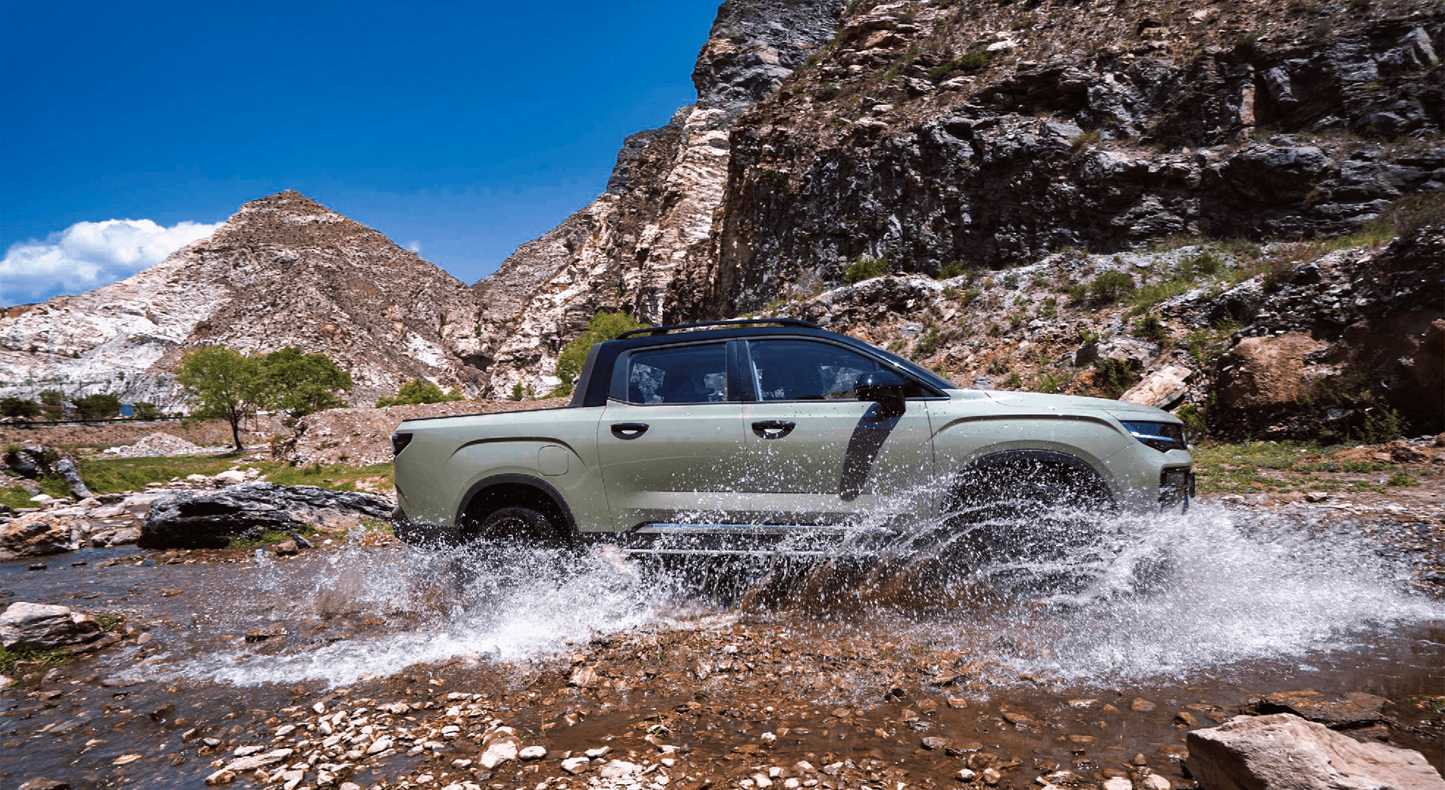 Geely Riddara driving through a rocky stream in mountain terrain